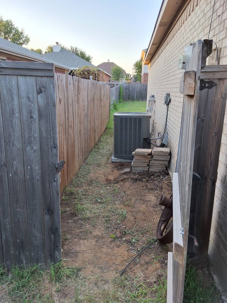 Narrow side yard between a wooden fence and a brick house